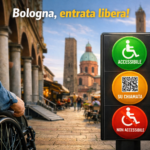 Scena di accessibilità Bologna: persona in carrozzina davanti ai portici e alle torri della città, con segnale semaforico di accessibilità e slogan ‘Bologna, entrata libera!